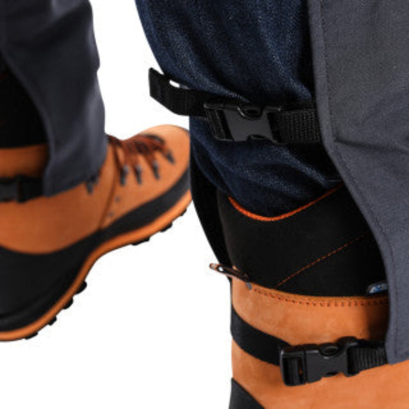 Close-up of back of clogger chaps showing clips with black straps on a white background
