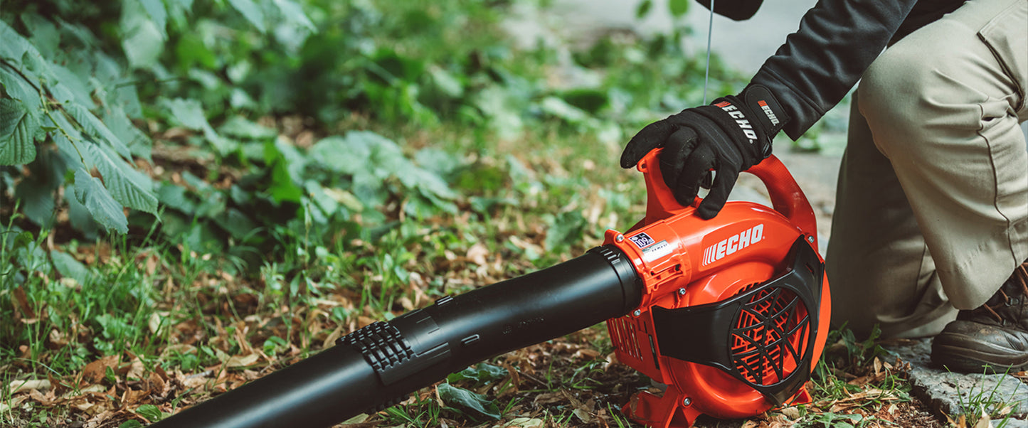 Person using a red and black Echo PB-2520 leaf blower in a forest setting