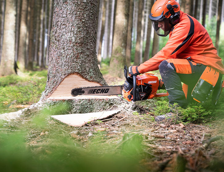 Person using an Echo CS-7310SX chainsaw to cut a tree in a forest, with 'ECHO' branding visible on the chainsaw.