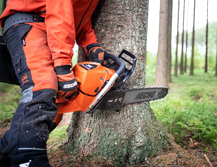 Person using an Echo CS-7310SX chainsaw to cut a tree in a forest setting