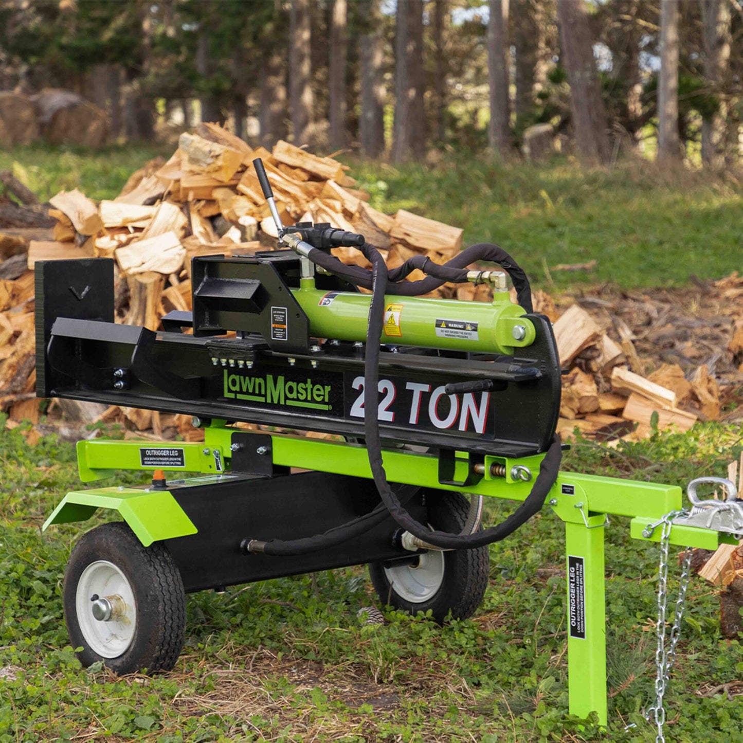 Green and black log splitter with 'LawnMaster' branding in a forest setting.