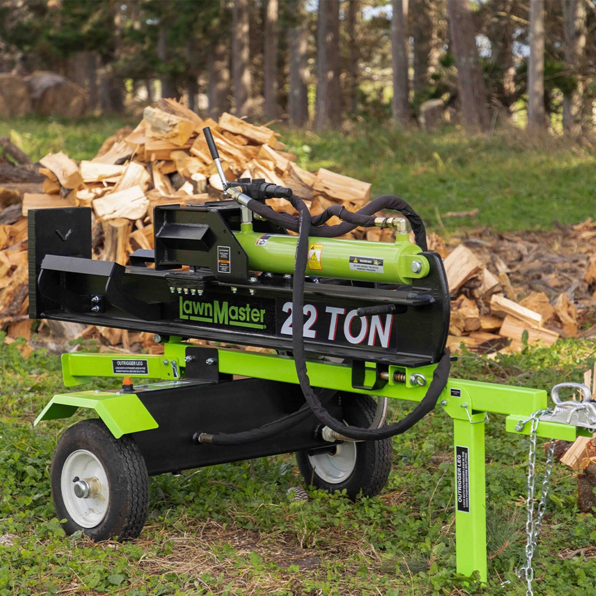 Green and black log splitter with 'LawnMaster' branding in a forest setting.