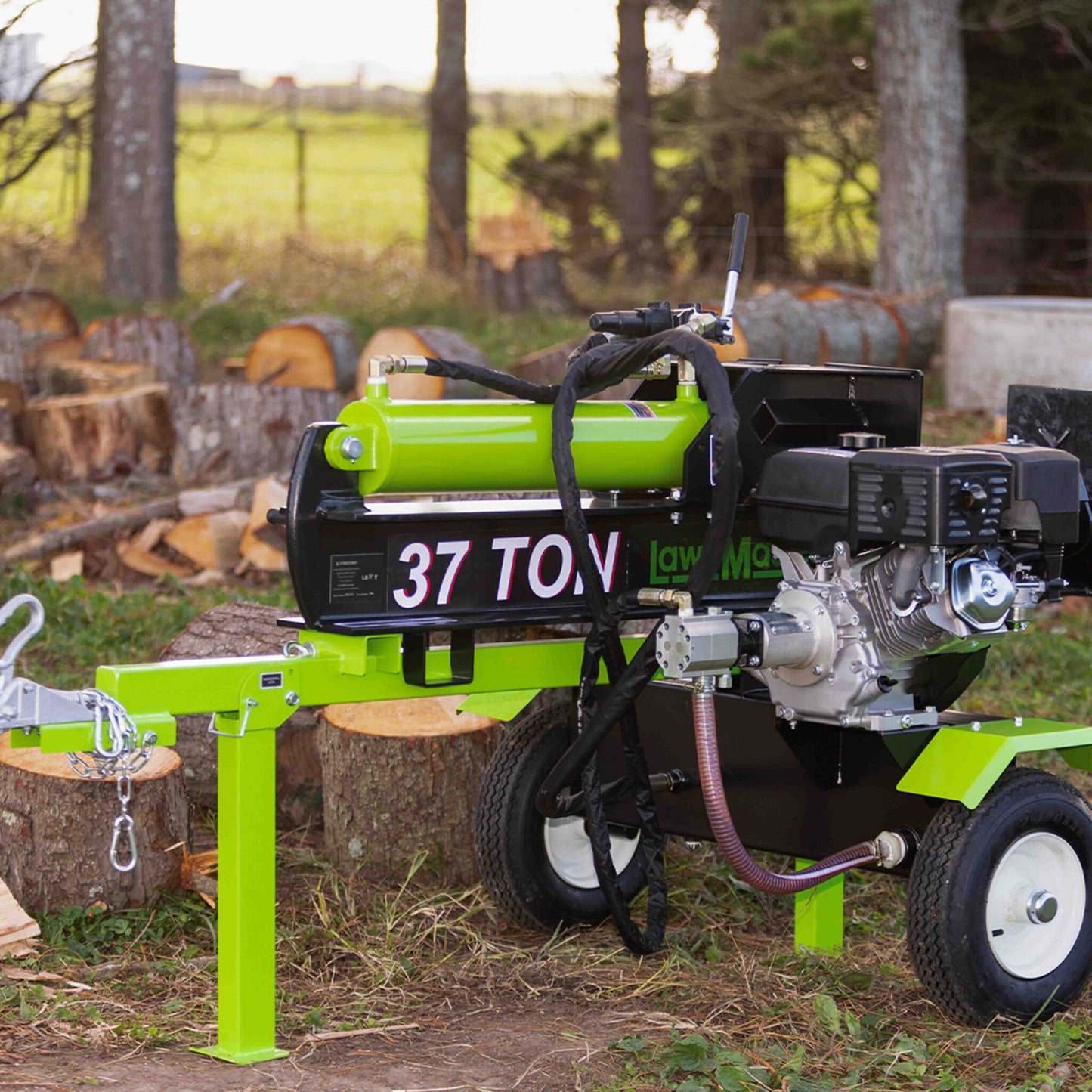 Green log splitter with '37 TON' marking in a forest setting