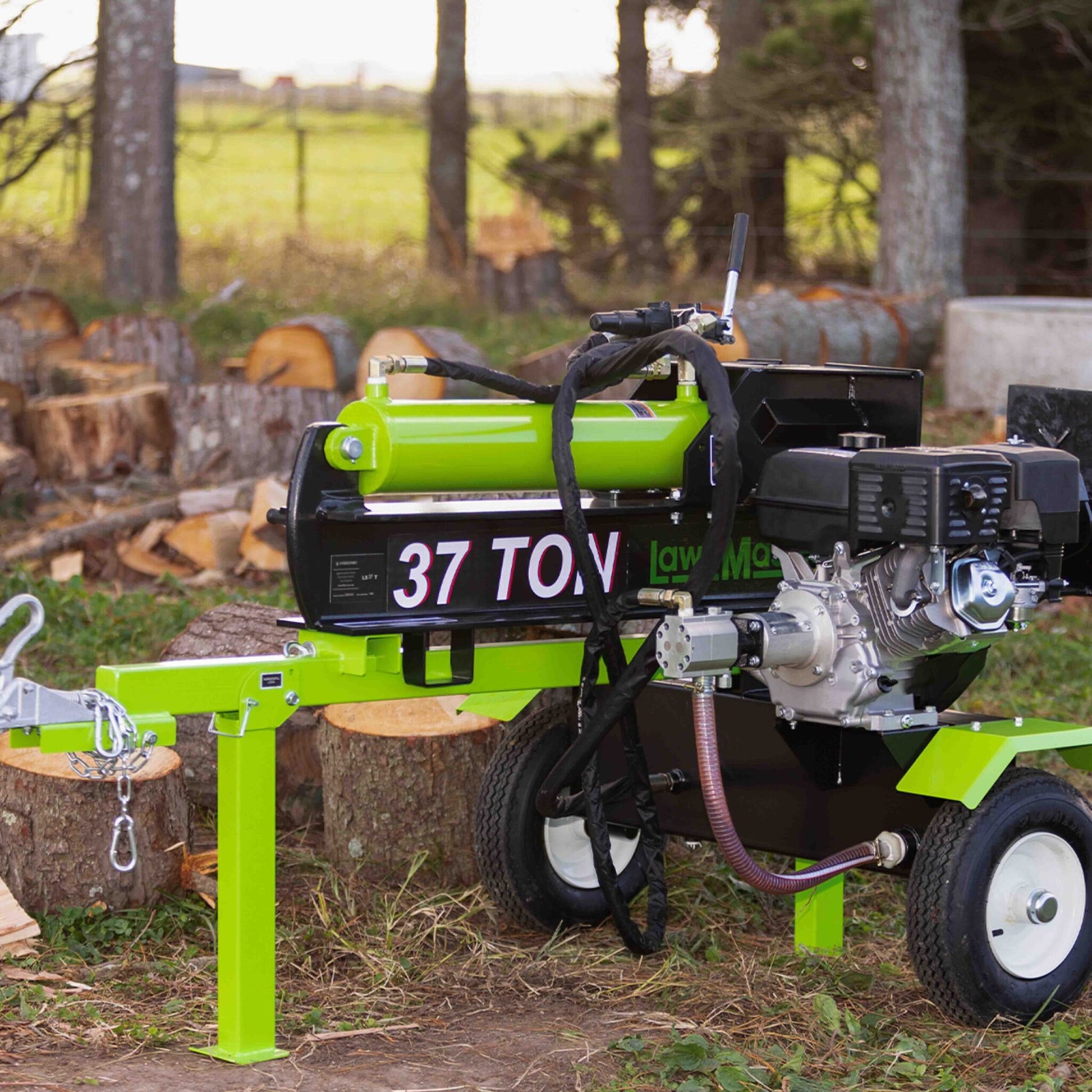 Green log splitter with '37 TON' marking in a forest setting