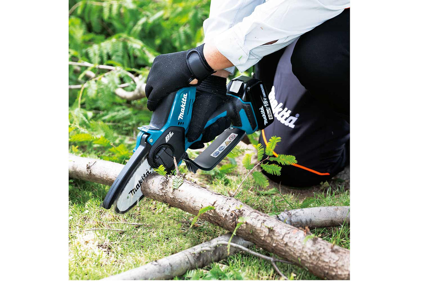 Image of person wearing black gloves while using Makita pruning saw to cut a branch.