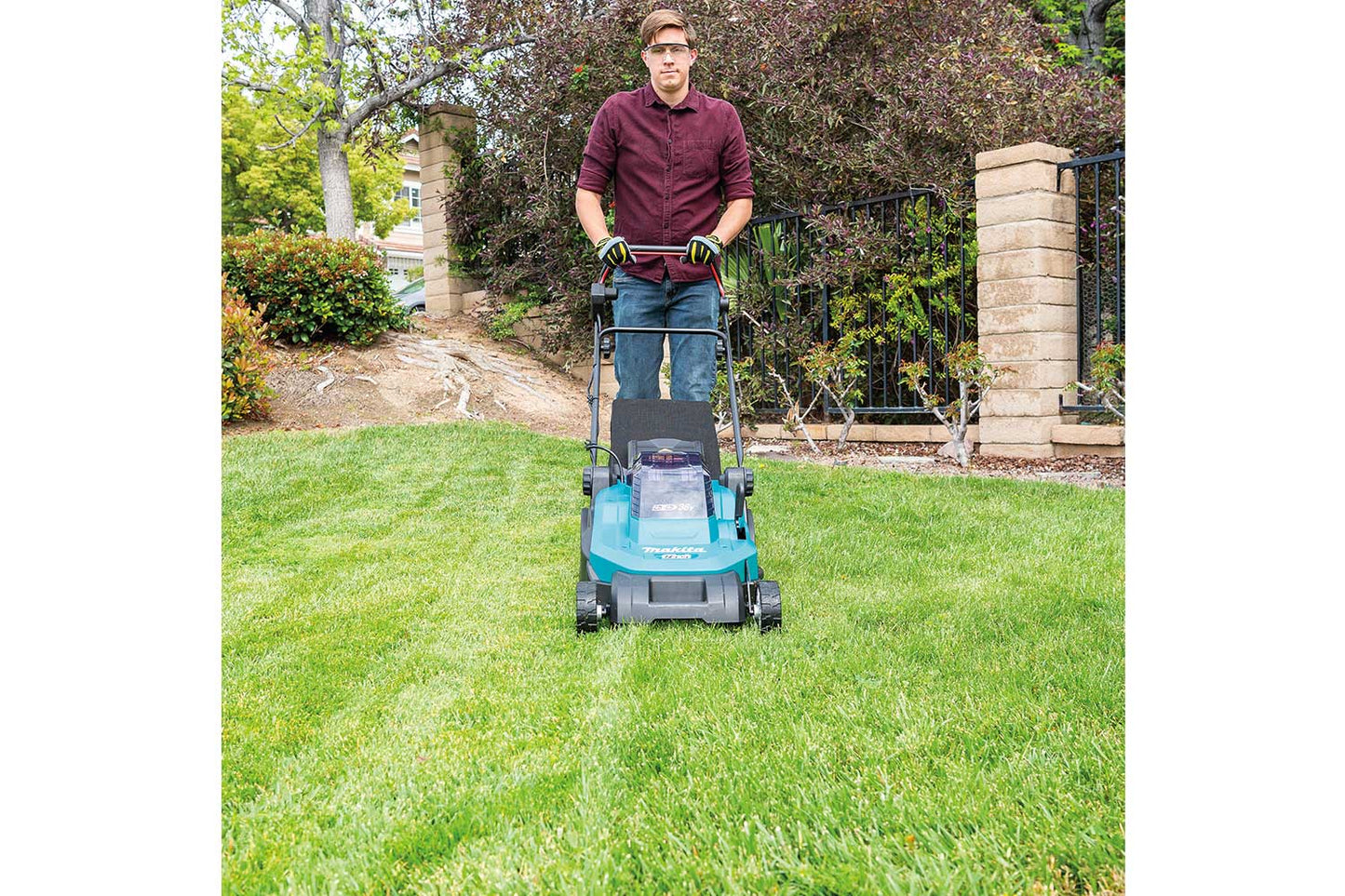Man mowing green lawns with a Makita lawnmower.